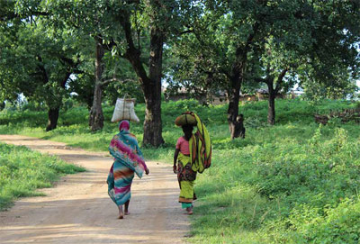 2 women walking down a dirt road in india
