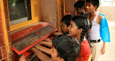 kids gathered around a computer embedded in a wall