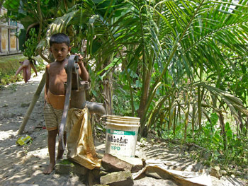 child standing next to a well pump, Bangladesh.