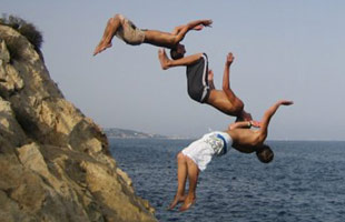 Teenagers diving off a rocky cliff