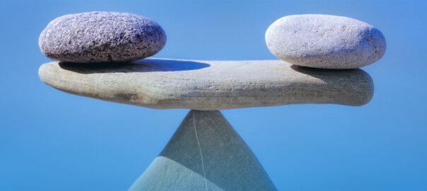 Two rocks balancing on a flat stone representing balance, stability and equilibrium.