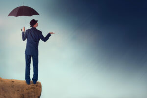 A businessman in a suit holding an umbrella and feeling the air for rain.