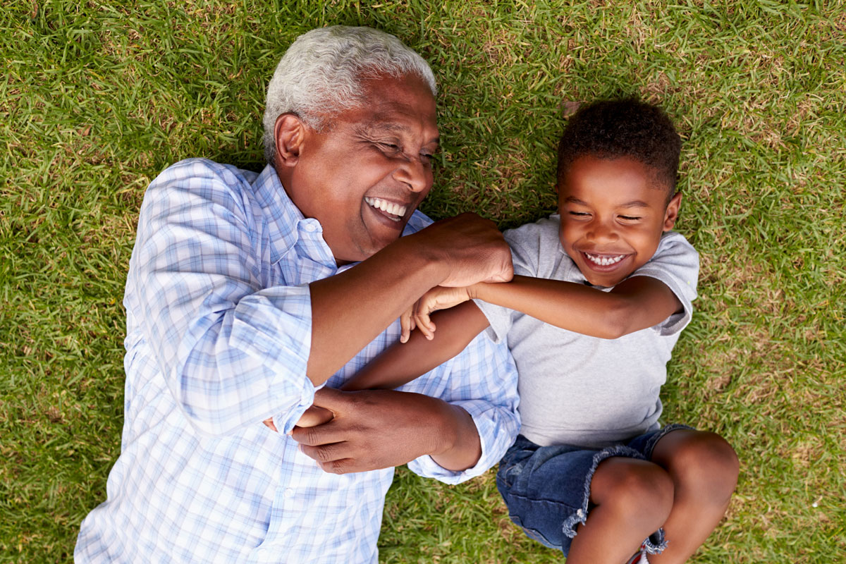 A healthy and happy grandfather and grandson play in the backyard.