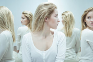 A woman in a room with multiple mirrors looking at different reflections of herself that represent different personalities.