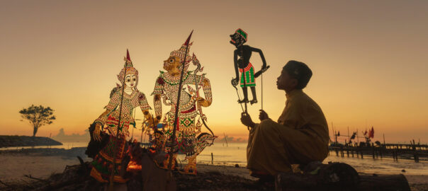 A boy in Indonesia telling a story using the tradition wayang shadow puppets of the region.