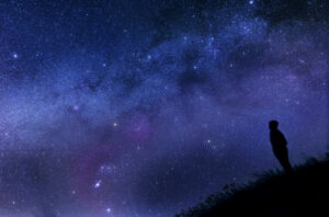 A photo of a person looking at the night sky and the stars.