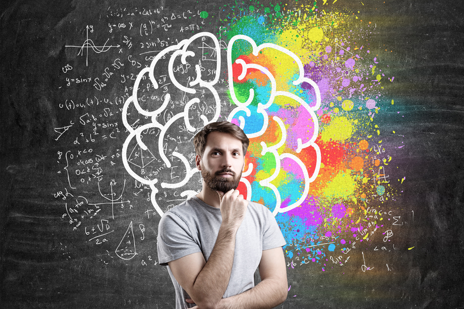 A man standing and thinking in front of an illustration of the right and left hemispheres of the brain.