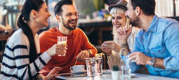 A photo of two couples socializing and laughing at a cafe.